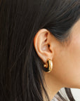 model wearing 14k gold fill chunky hoop studs. 