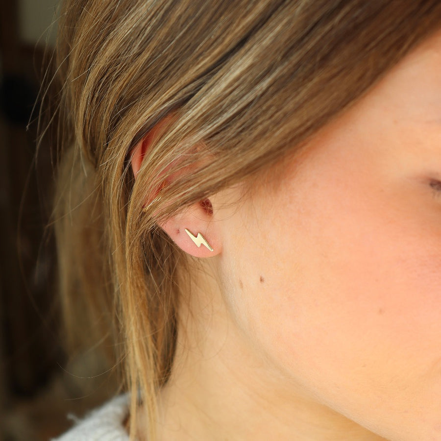 gold fill lightning bolt stud earrings pictured on a model