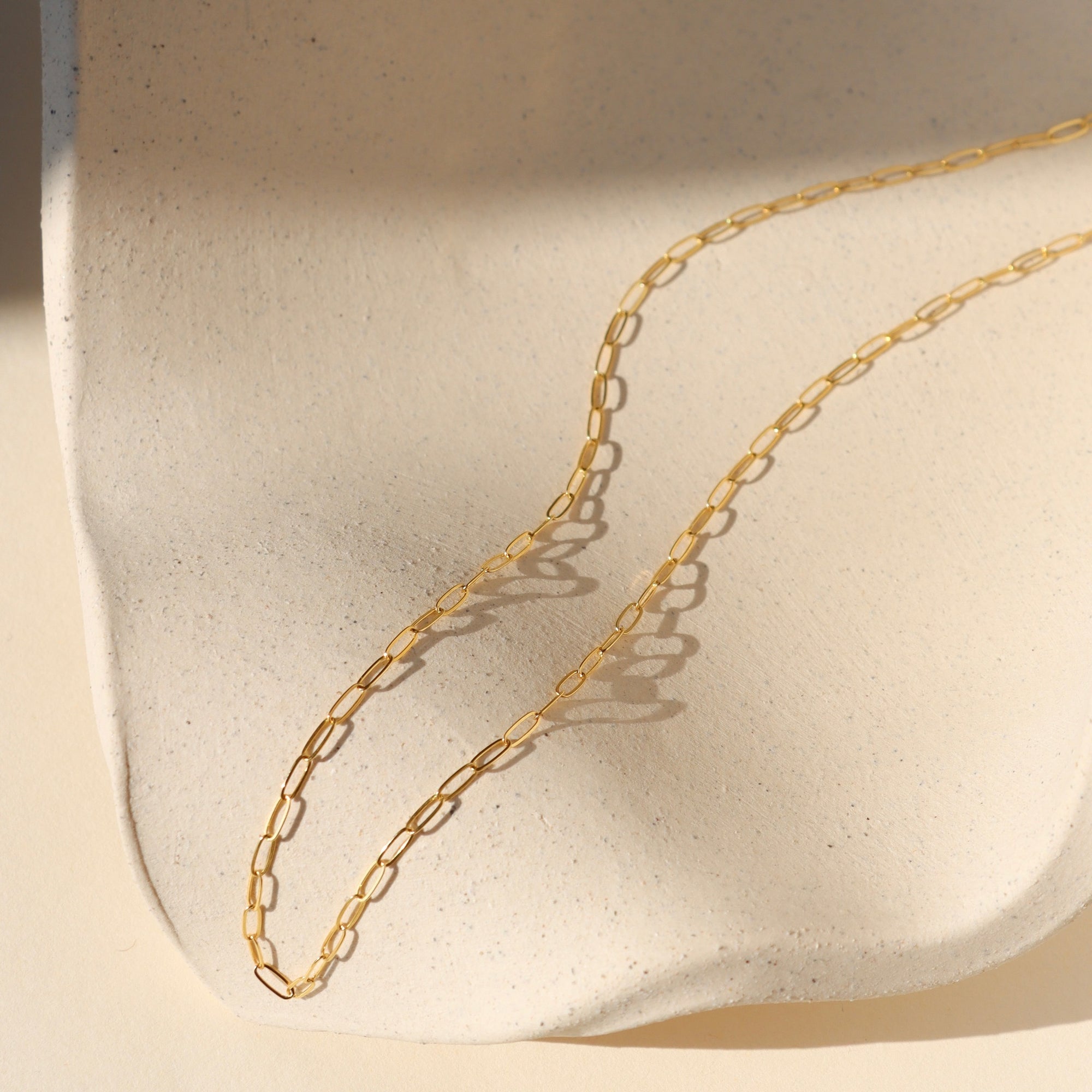 14k gold fill delicate cosette chain on wavy dish in the sunlight