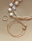 Margot ring laid on a plate paired with a Pair of Emma hoops and the Evelyn pearl necklace