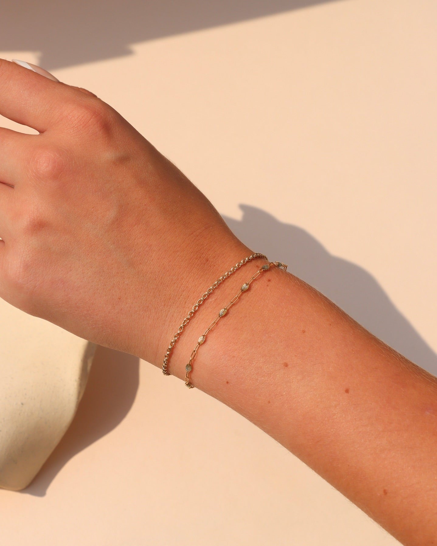 Labradorite Gemlink Bracelet layered with a delicate gold chain bracelet, styled on the wrist in warm sunlight.