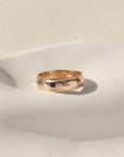 A gold hammered band with rippled edges. Displayed on a small ring dish. 
