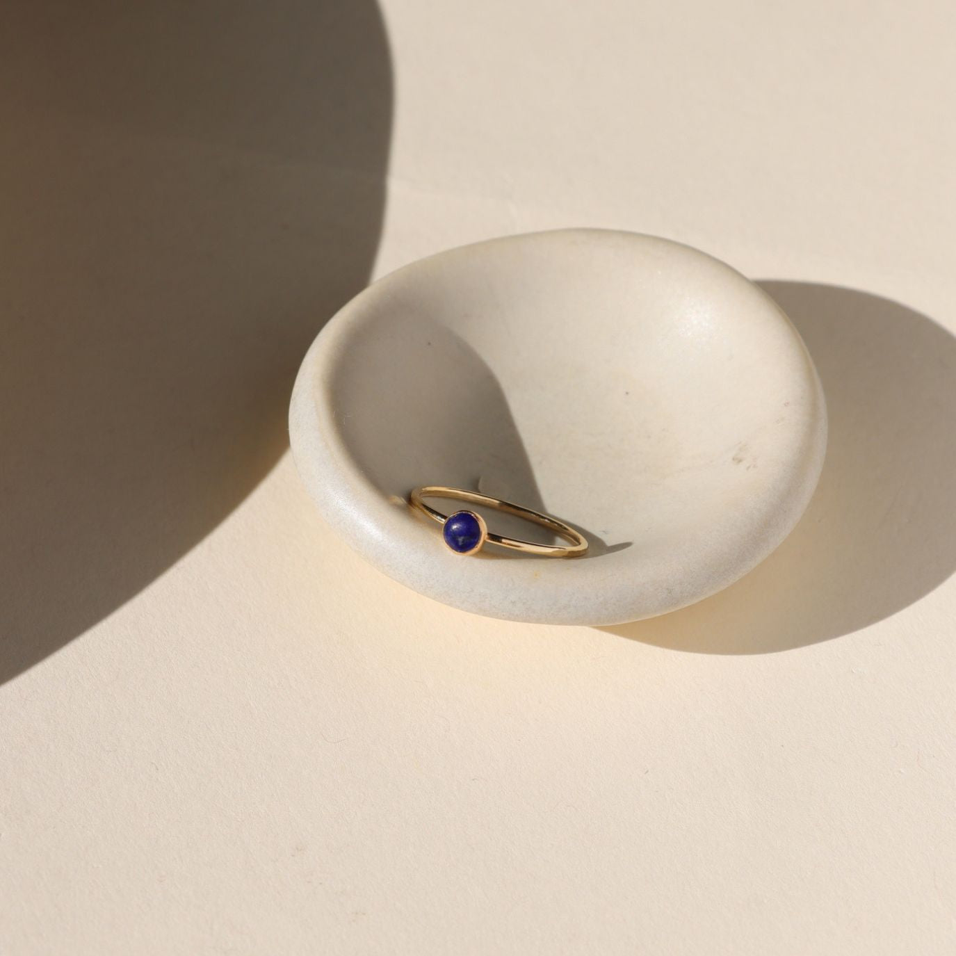 14k gold fill bezel ring with a 4mm lapis lazuli stone on a light dish