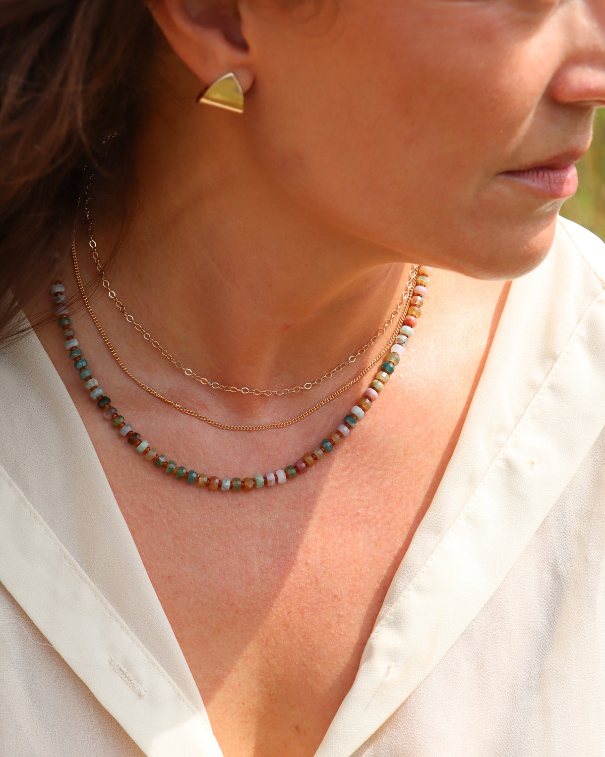 Gold-filled oval-link chain necklace layered with a delicate gold chain and multicolor gemstone beaded necklace, styled with gold stud earrings.