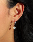 model wearing mother of pearl heart charm in sterling silver on simple sterling silver hoop