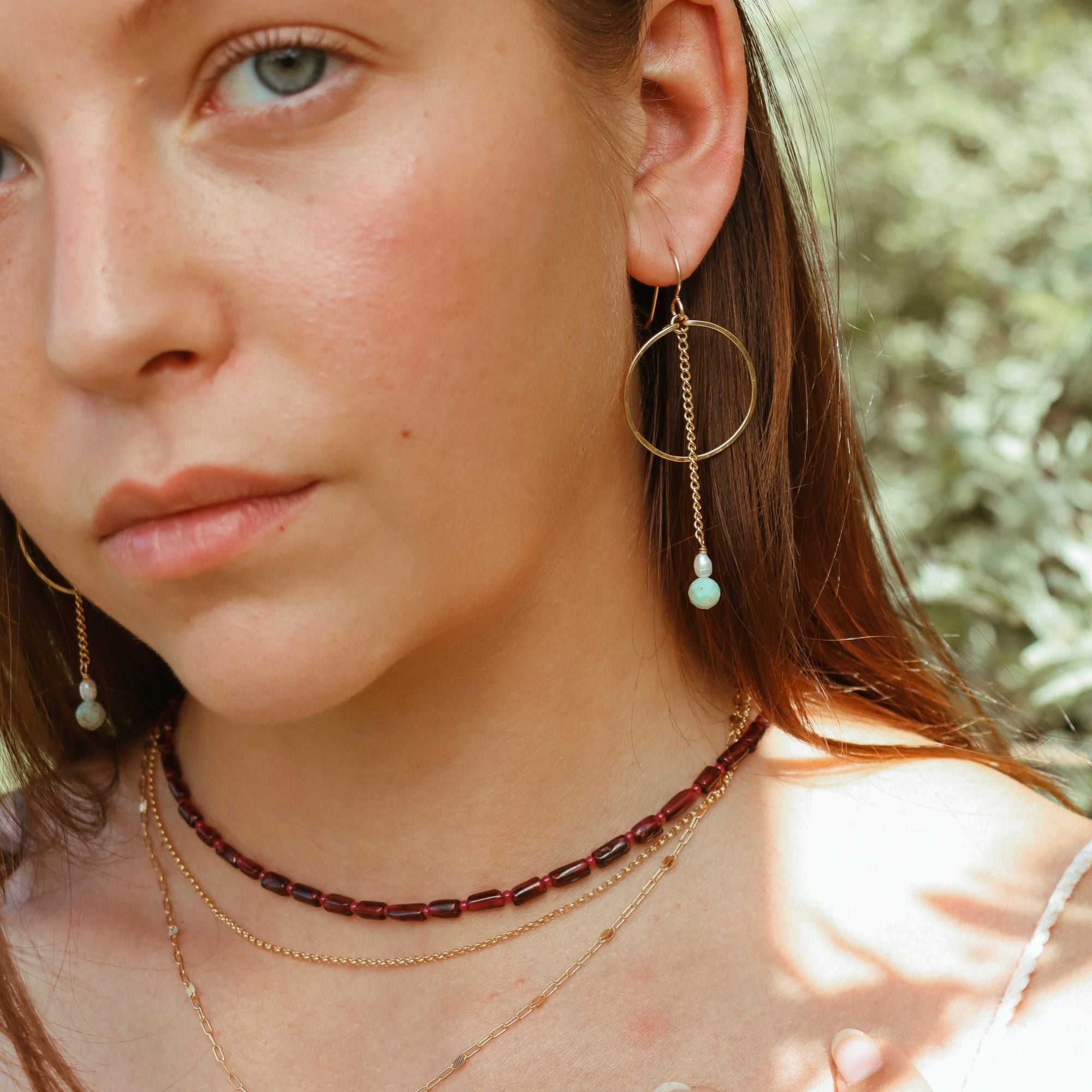 model wearing 14k gold fill hoops with pearls and turquoise beads with beaded garnet necklace and chain necklaces