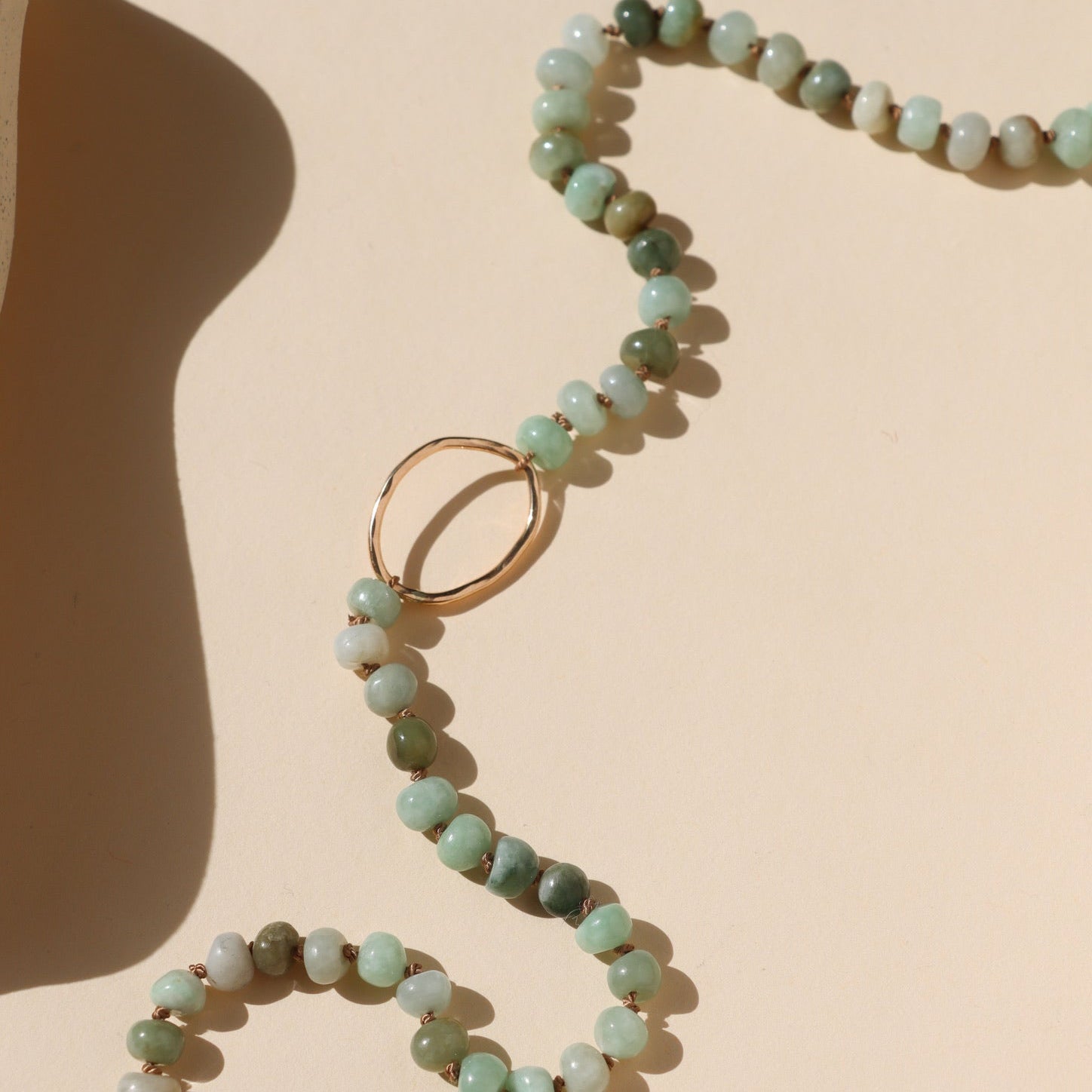 handmade circle pendant with jade beads on a light background