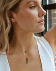 Gold hand stamped, area code necklace with delicate chain, paired with a thin labradorite gemstone necklace worn by the model. 