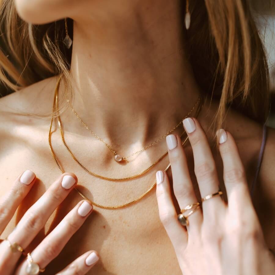 Model wearing 14k gold fill Necklace in the sunlight. Model is also wearing multiple necklaces and rings.