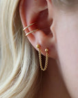 Two gold ball posts connected with a curb chain. Model is also wearing a double ear cuff with a thin wire. 
