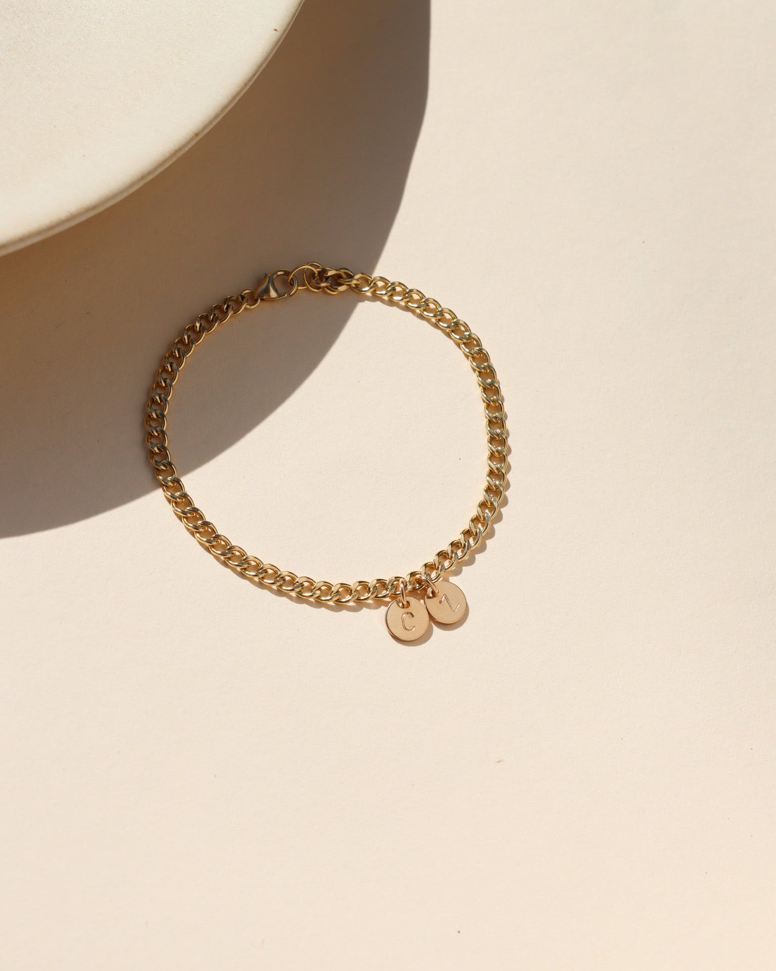 14k gold fill curb chain bracelet with hand stamped round disc charms on a light table