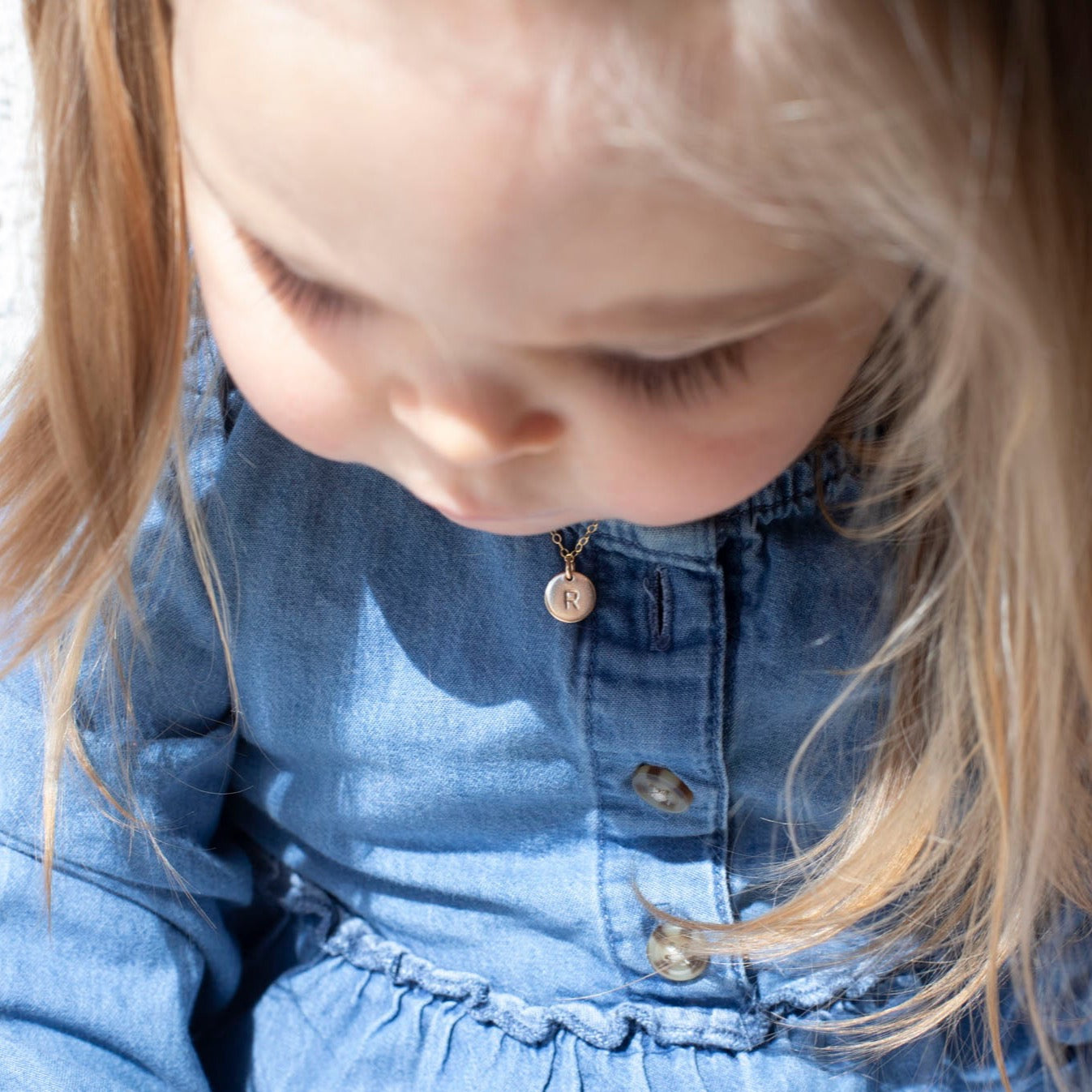 Model wearing 14k gold fill Tiny Monogram Disc Necklace. This necklace features our simple chain with a disc pendent with a heart stamped on it.