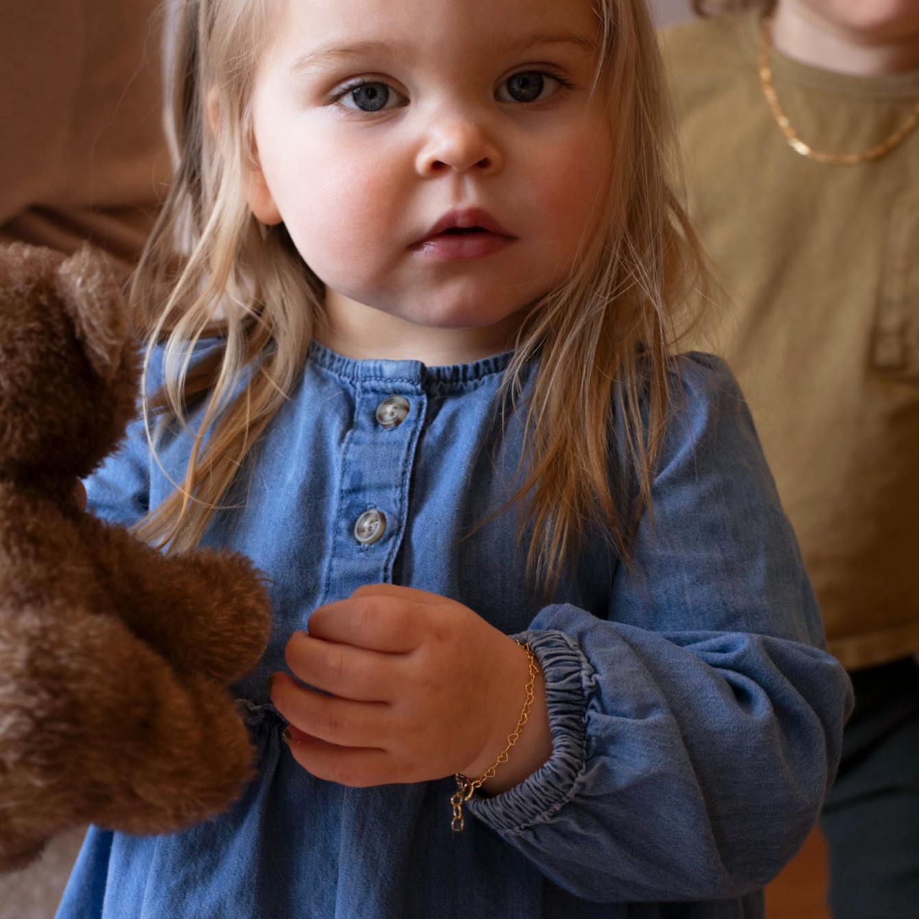 14k gold fill heart link chain in children&#39;s sizes, photographed on a little girl wearing a blue denim dress and holding a teddy bear