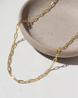 14k Gold fill Narrow Links chain laid on a white paper in the sunlight.