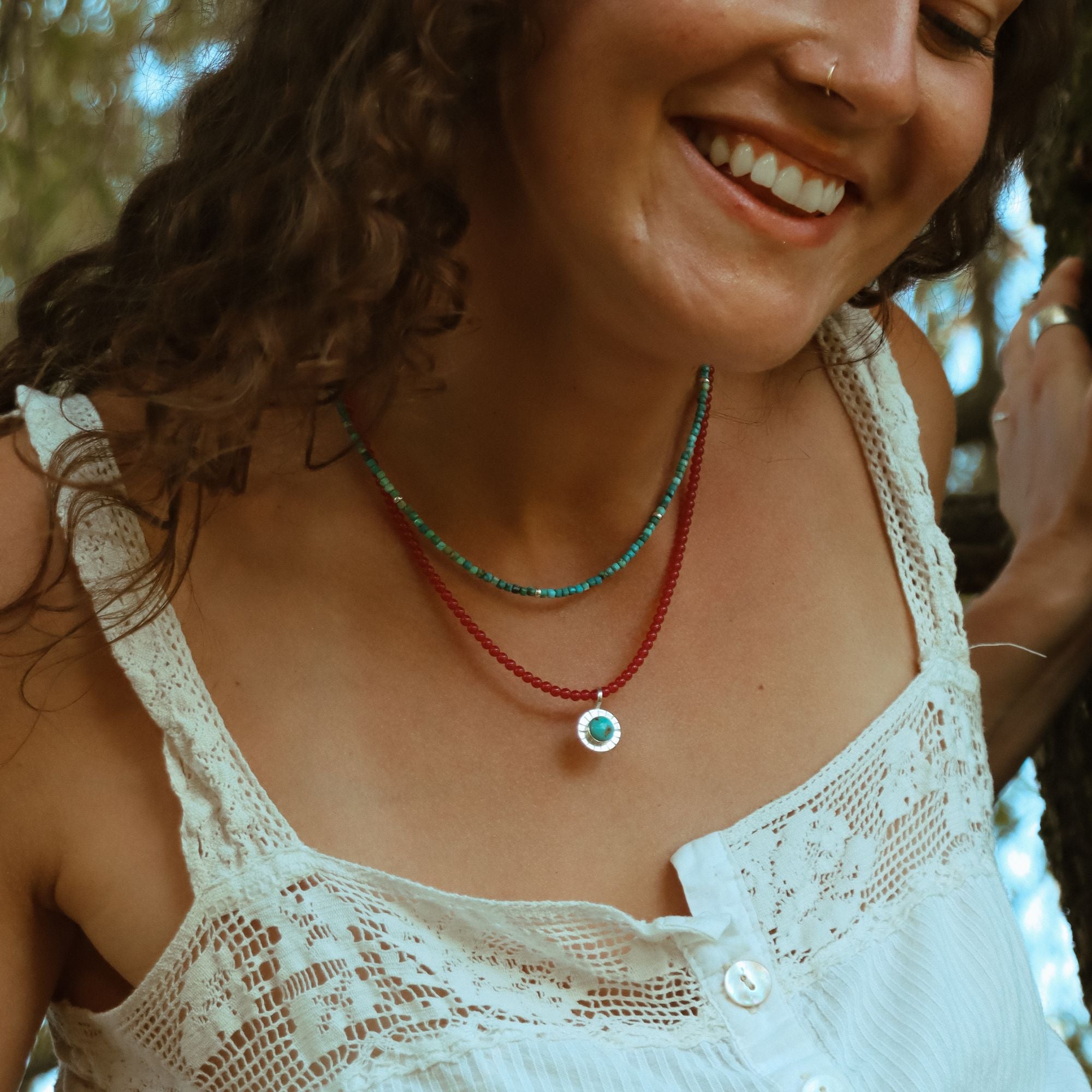model wearing turquoise and ruby beaded necklaces with round turquoise pendant
