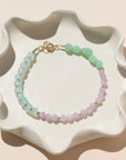 A 14k gold fill bracelet with a mixture of Turquoise, Kunzite, Chrysophrase, Serpentine, and Calcedony Gemstones. The bracelet is displayed on a white back drop in the sunlight. 