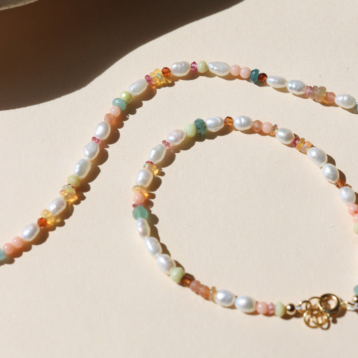 hand beaded bracelet with Pearl, Coral, Opal, Hessenite, Grandidenite, Tourmaline, Moonstone on a light dish