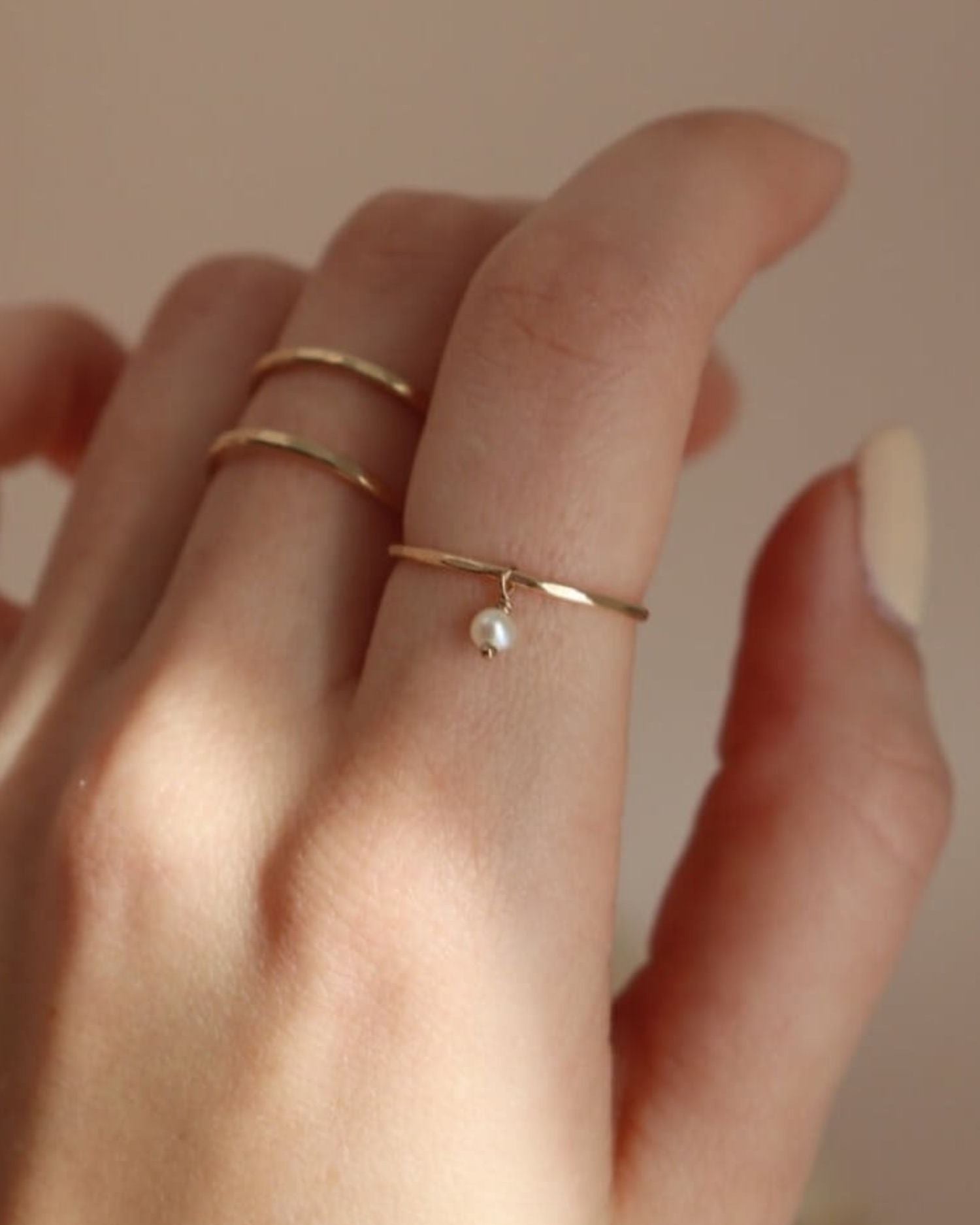 model wearing gold rings with with pearl bead in the warm sunlight