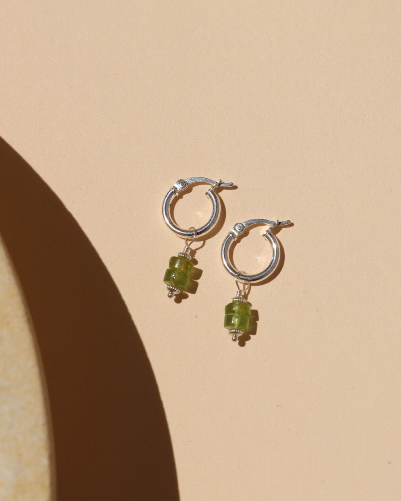 silver hoop earrings with peridot bead drops in the sunlight