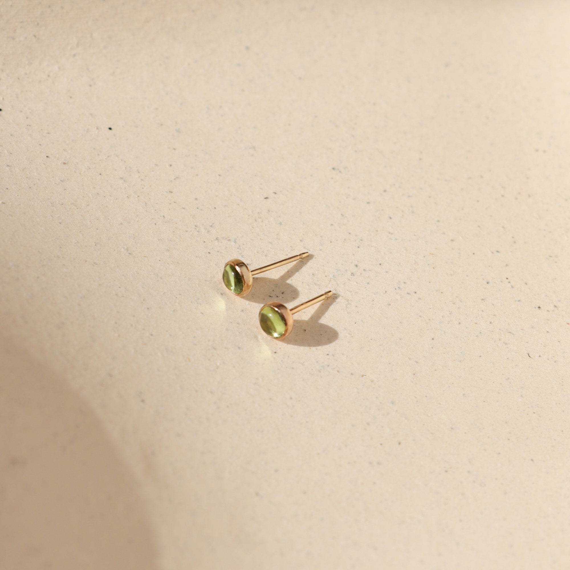 14k gold fill bezel ear post with 4mm peridot stones in the sunlight