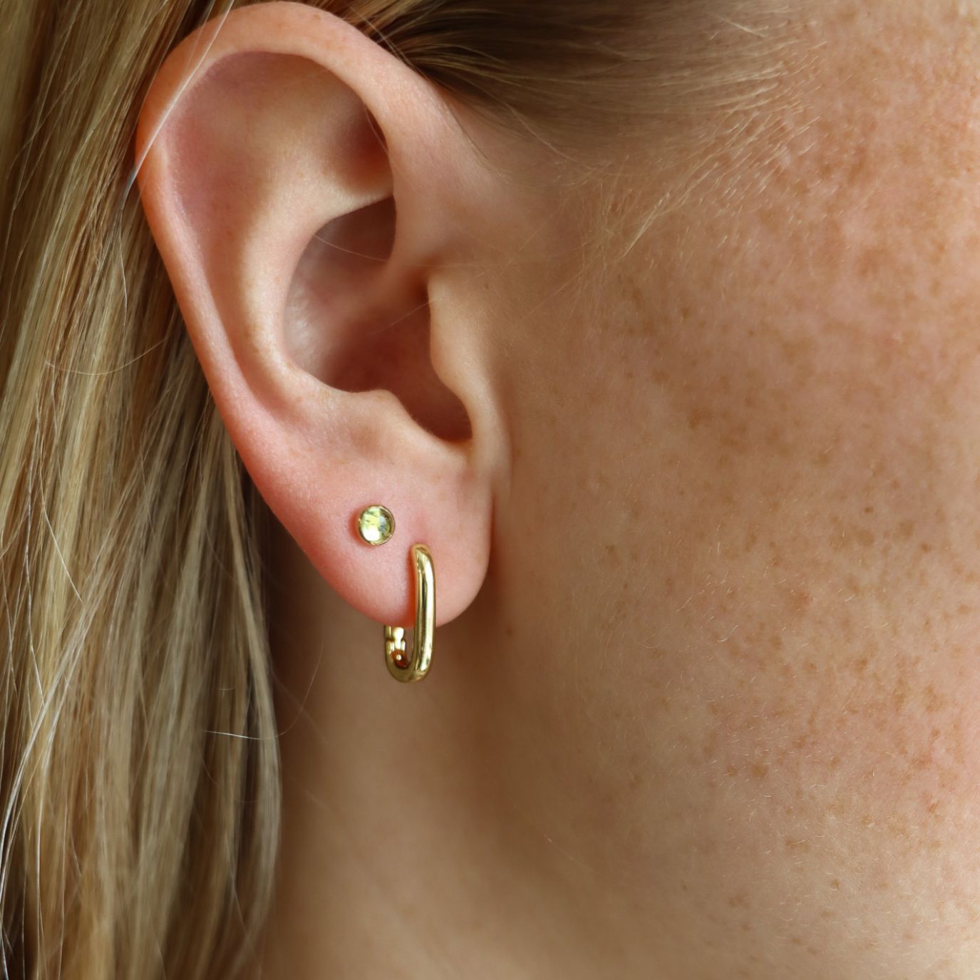 model wearing 14k gold fill huggie hoops with round peridot studs