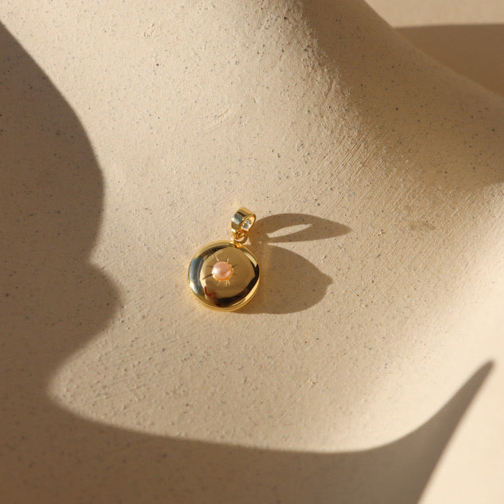 PInk Pearl Locket on tan dish in sunlight