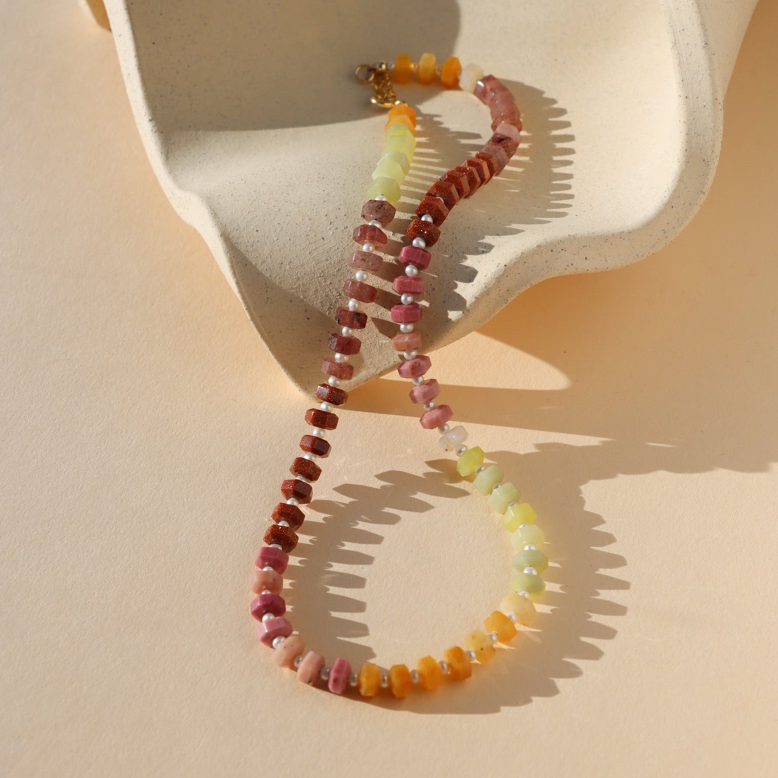 multi colored beads with pearls necklace on wavy plate in the sunlight