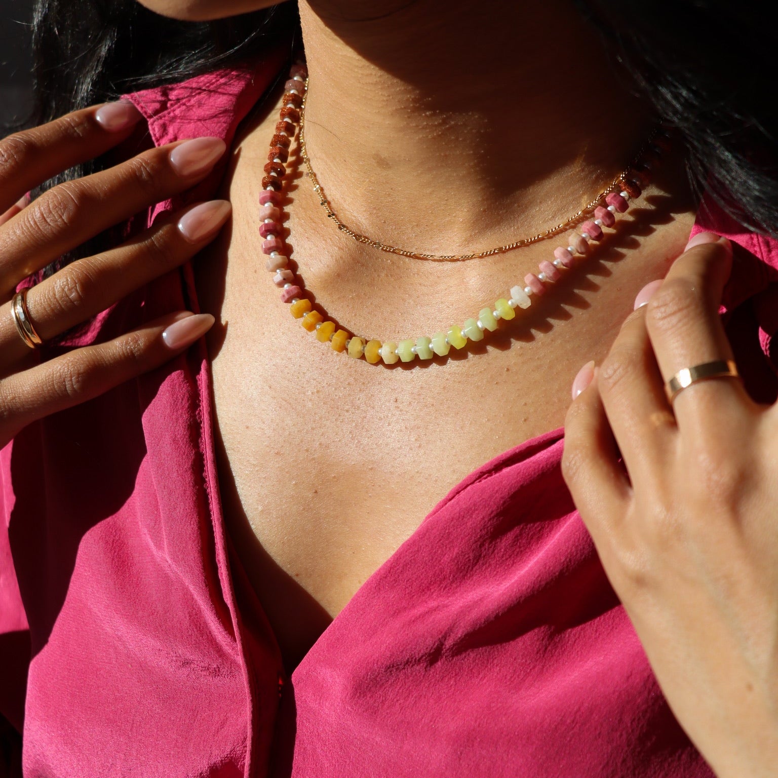 close up of model wearing multi colored bead and pearl necklace layered with 14k gold fill chain