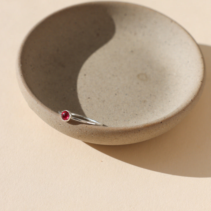 sterling silver bezel ring with 4mm ruby gemstone on a light dish