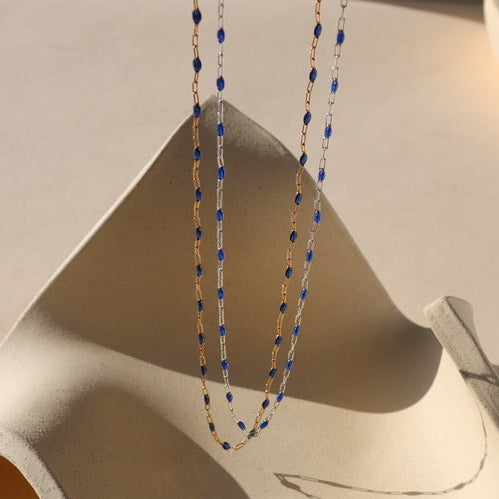 14k gold fill chain with sapphire gemstones paired with sterling silver chain with sapphire gemstones hanging with a light background