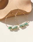 A 1.75 wide 14k gold fill wire hoop with three amazonite gemstones wire wrapped at the bottom of each earring. Earrings are displayed on a cream back drop. 