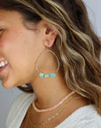 A model wearing a 1.75 wide 14k gold fill wire hoop with three amazonite gemstones wire wrapped at the bottom of each earring. 