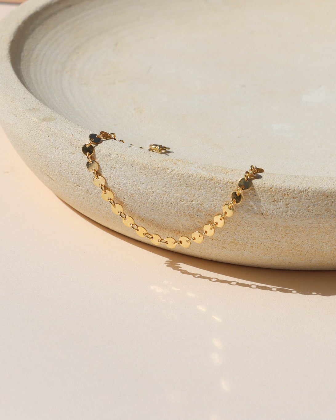 Starlight Bracelet featuring polished disc chain links styled on a textured ceramic form in natural light.