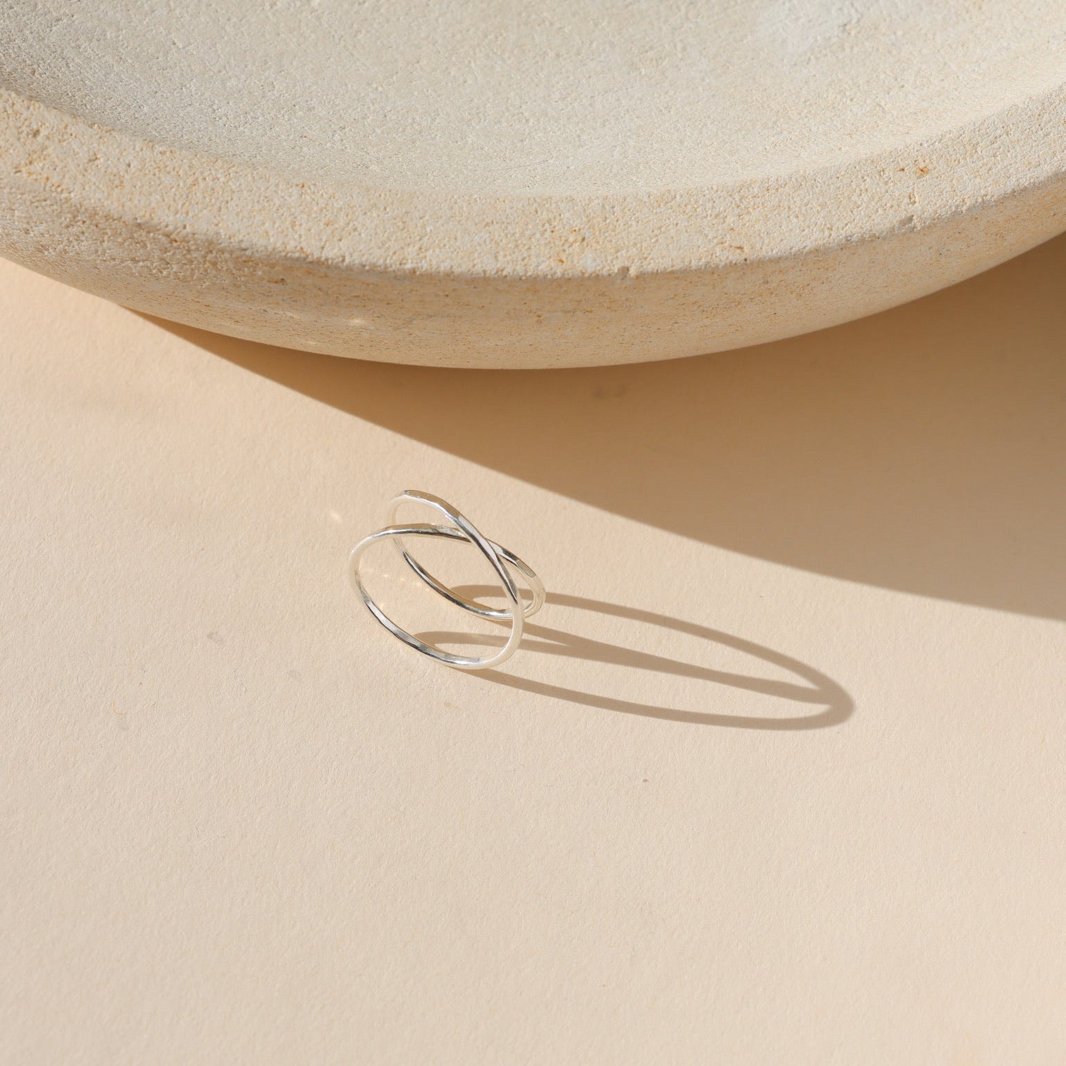 Sterling silver open wrap ring with a modern overlapping band design, minimalist everyday stacking ring photographed in natural light.