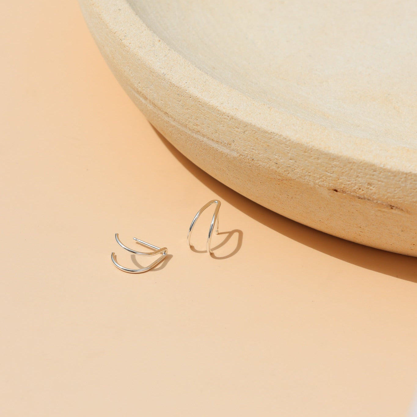 Sterling silver minimalist stacking ring with a thin polished band, modern everyday jewelry displayed on a ceramic jewelry tray in natural sunlight.