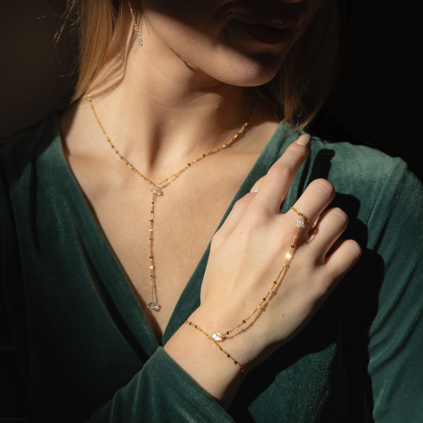 Gold sunburst hand chain featuring delicate textured links and a raw Herkimer diamond accent.