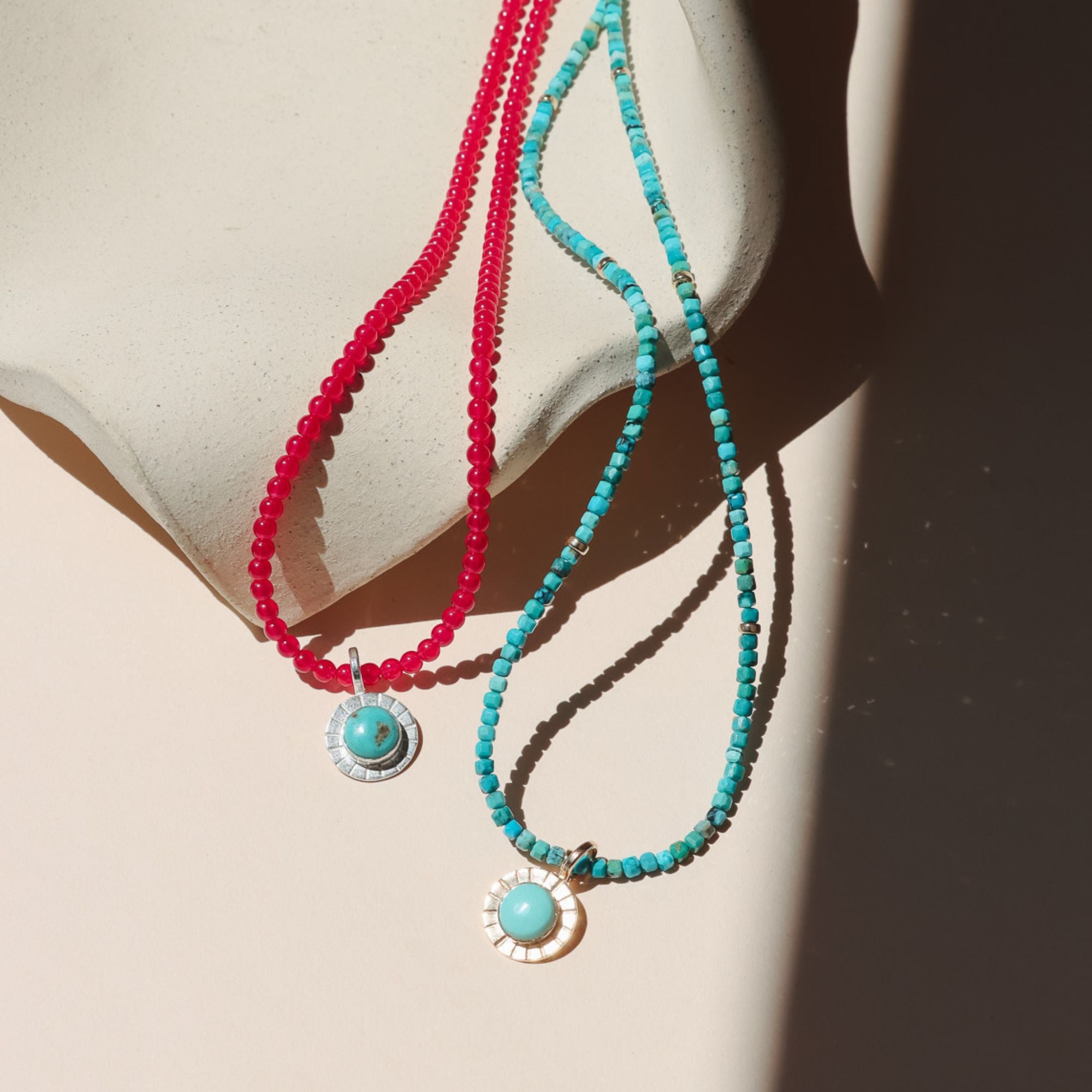 photo showing a round turquoise pendant on two different beaded necklaces