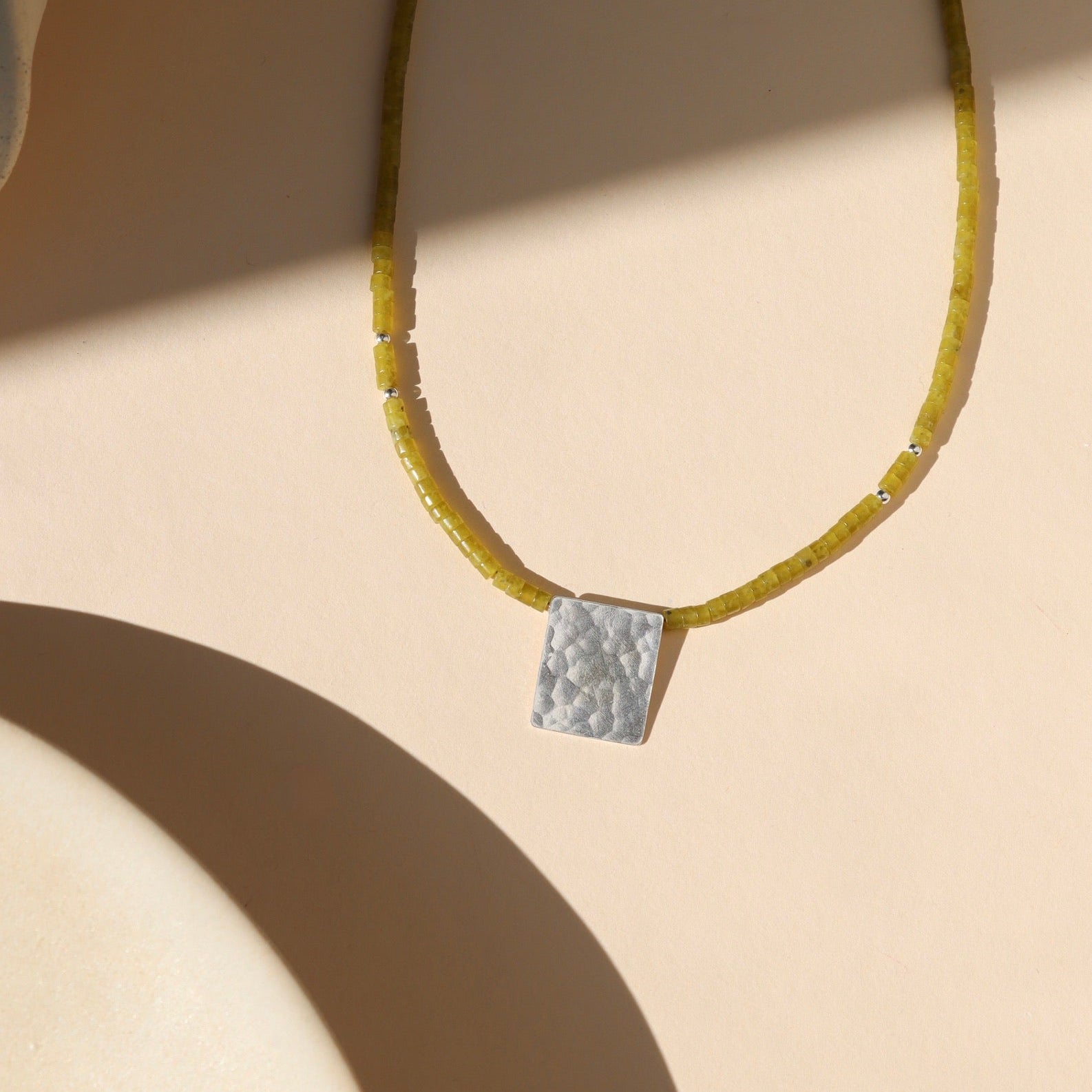 jade beaded necklace with a sterling silver pendant on a light background