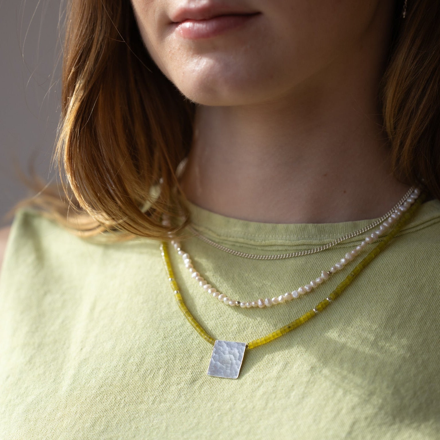 model wearing jade beaded necklace with sterling silver hammered pendant and beaded pearl necklace