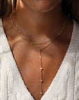 Model wearing a 14k gold fill bar and link chain with three peach opal gemstones. 
