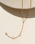 A 14k gold fill bar and link chain with three peach opal gemstones in a lariat style necklace. 