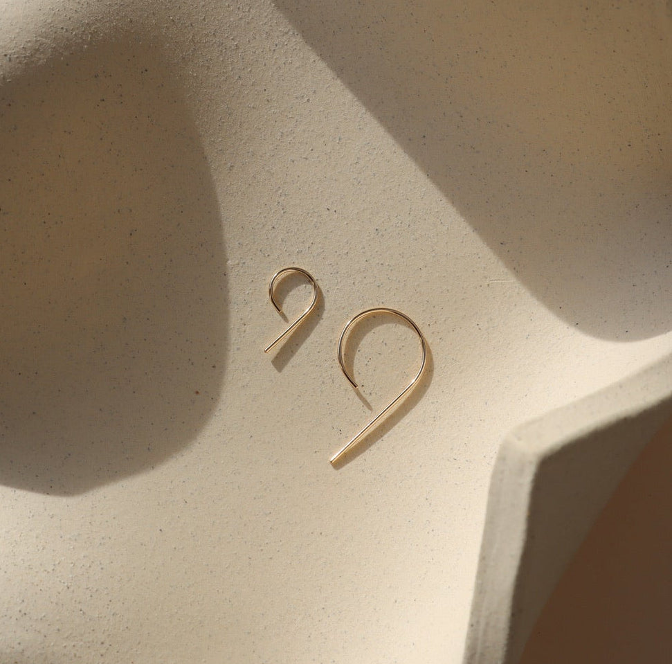 14k gold fill 9 shaped earrings in 2 sizes on a light dish