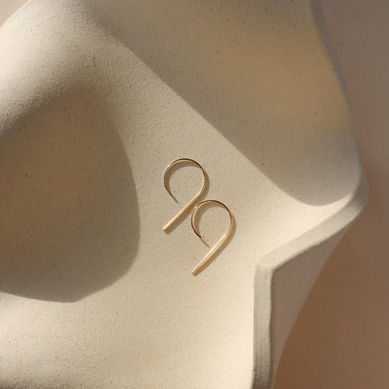 14k gold fill nine shaped earrings on a light dish