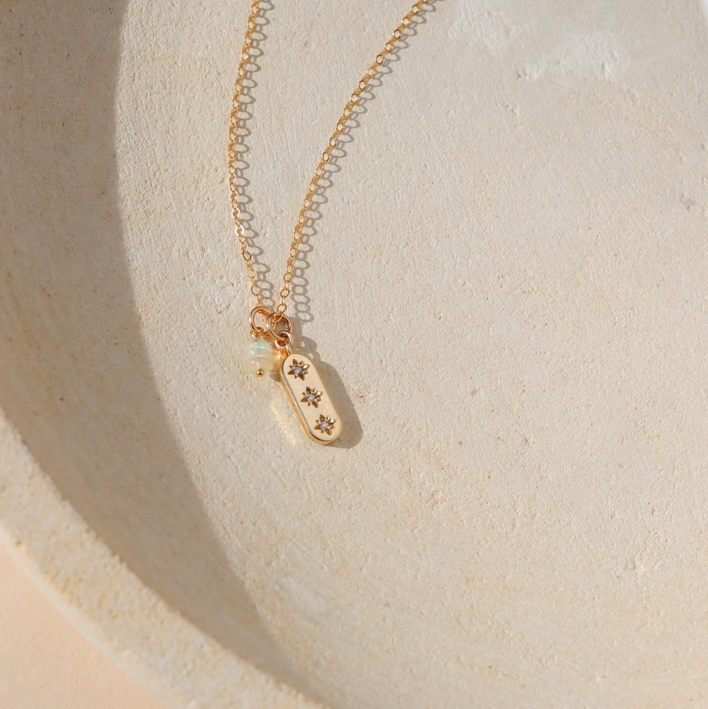 Close-up of three opals in a minimalist gold bar necklace with stacked opal bead detail