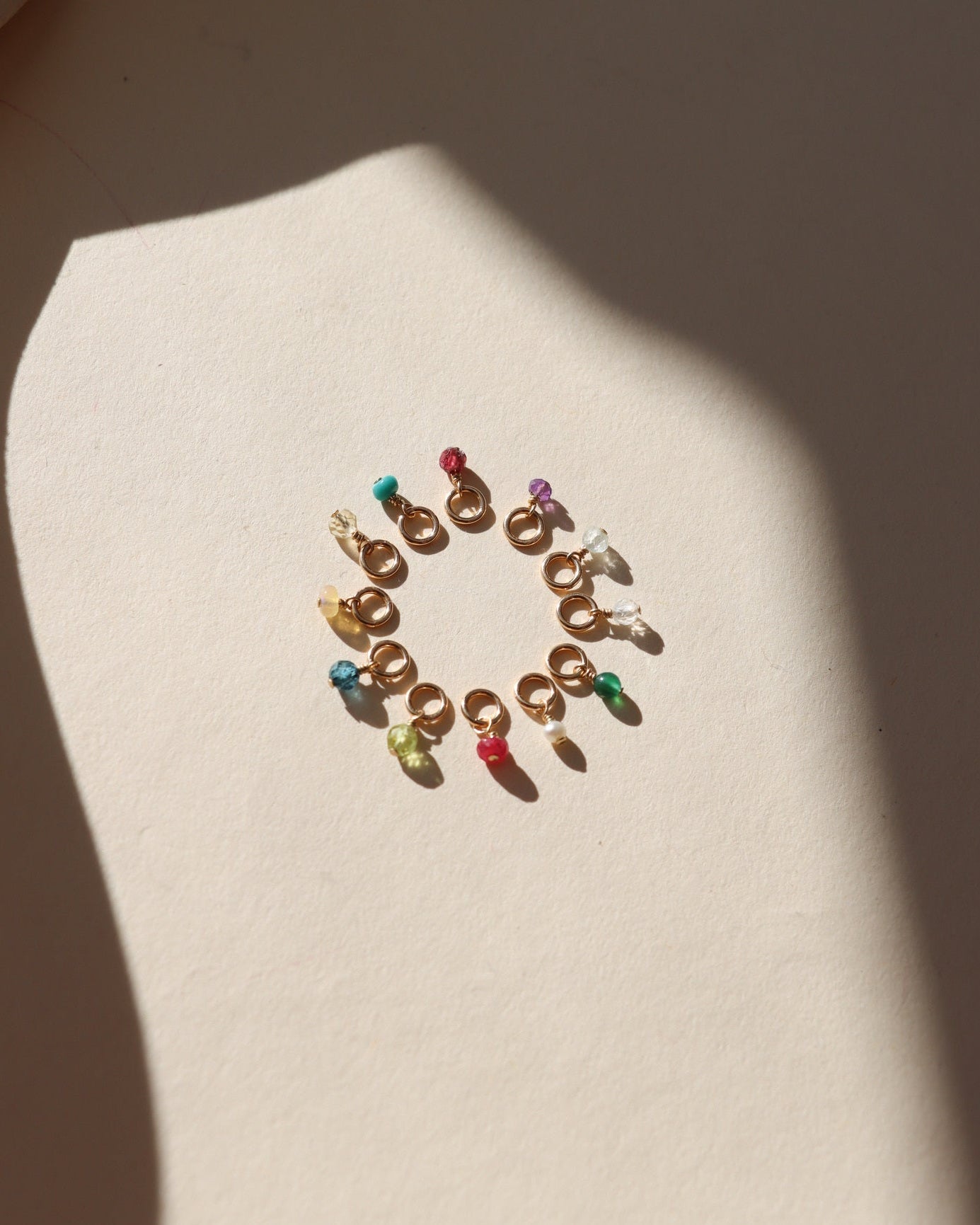 circle of tiny birthstone gemstones on jump rings in the sunlight