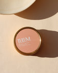 candle in peach colored tin in the sunlight