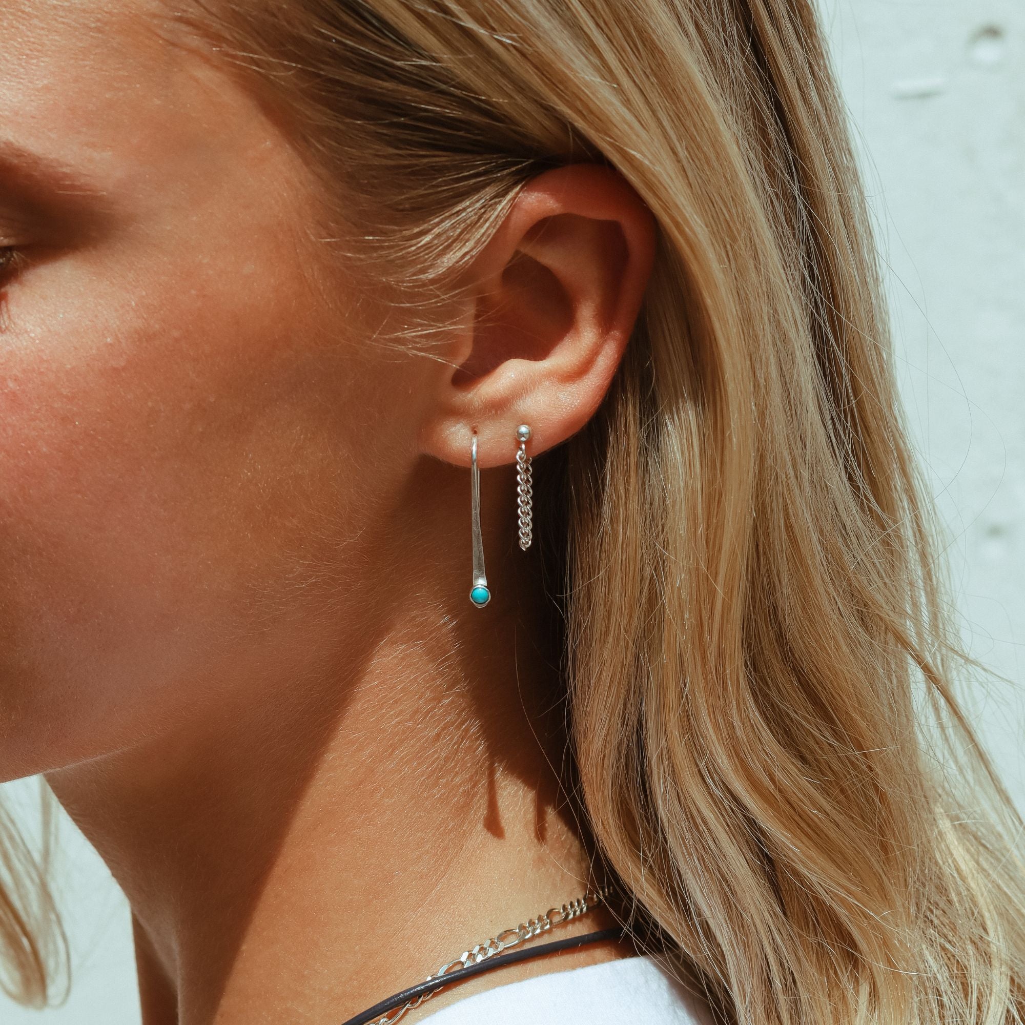 model wearing sterling silver arch shaped earrings with round turquoise stone