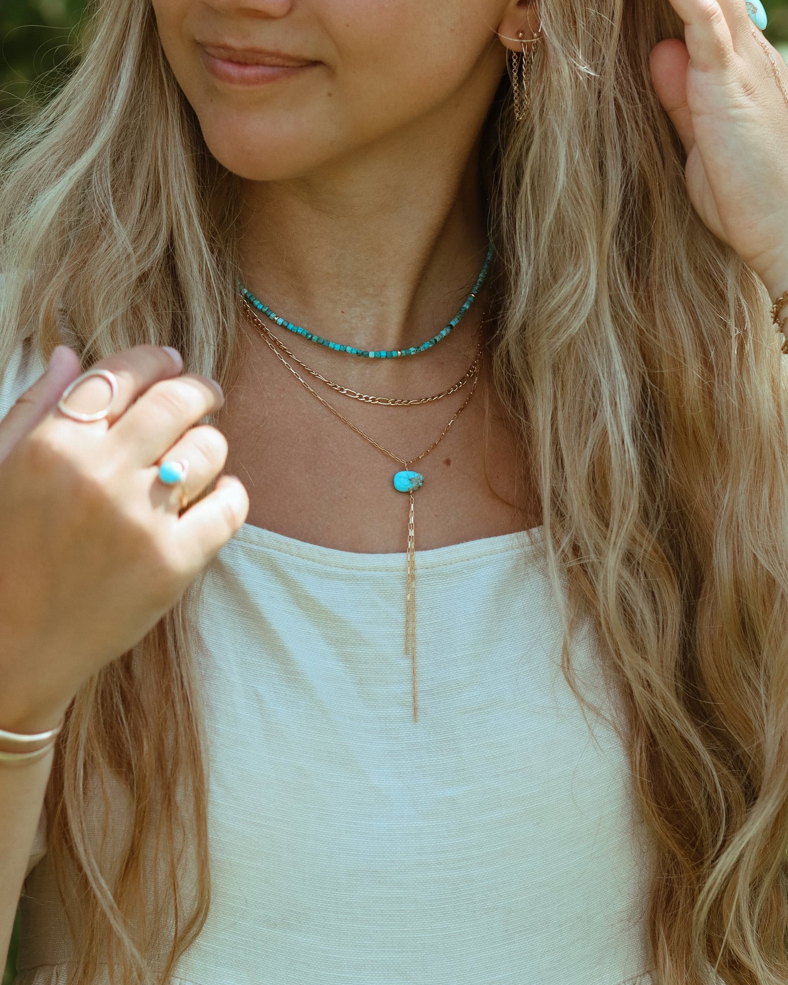 Turquoise Gemstone beaded necklace layered with a 14k gold fill chain necklace and a gold filled lariat with a turquoise stone anchored in the middle on a model.