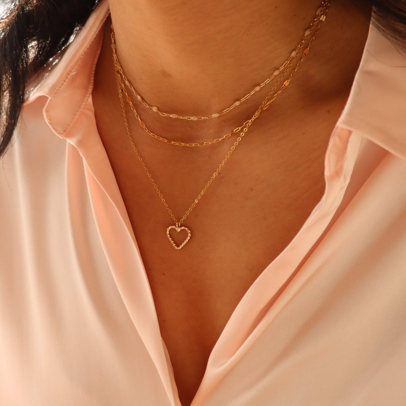 model wearing 14k gold fill spiral wire heart shaped pendent necklace layered with simple paperclip chain 14k gold fill necklaces