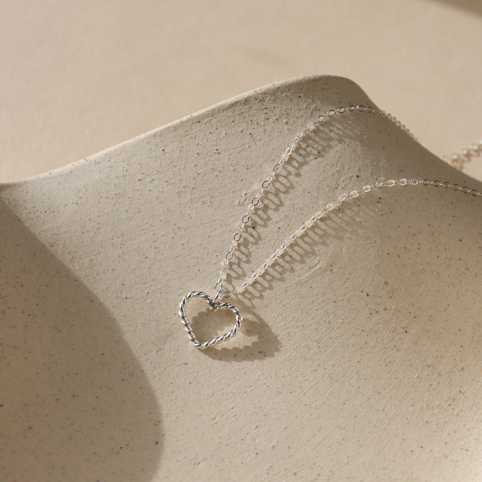 sterling silver spiral wire heart shaped pendent on simple sterling silver chain in the sunlight